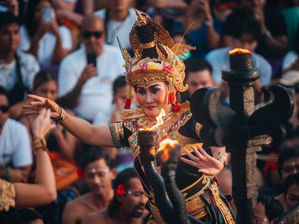 Hanuman leaping above the seated Kecak chanters beside a lit fire lamp